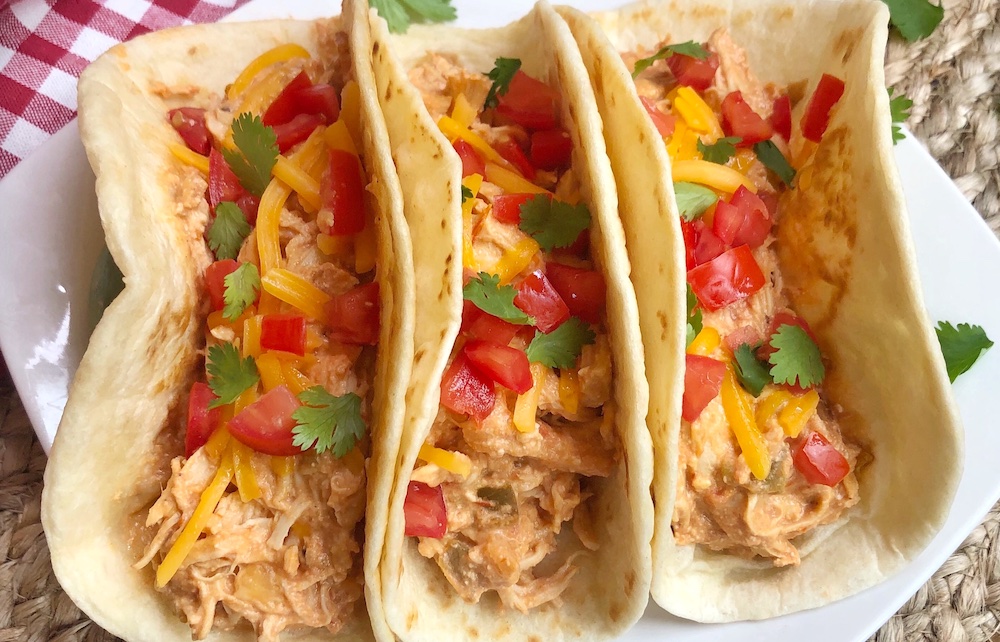 Creamy shredded crockpot chicken made with salsa and cream cheese! This easy slow cooker recipe is perfect for making delicious tacos.