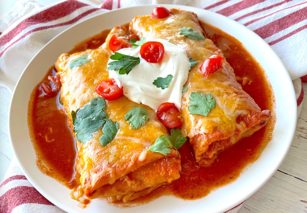 How to make frozen burritos awesome! Simply bake them in a casserole dish smothered in enchilada sauce and cheese. A super quick and easy weeknight dinner for a family with kids.