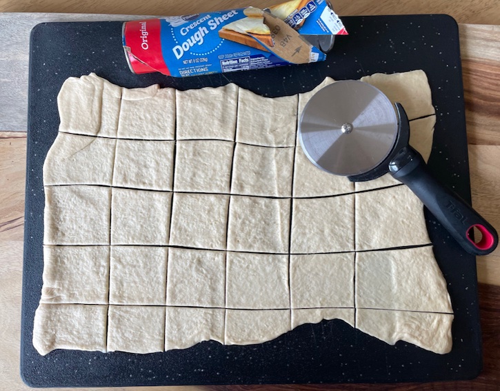 Cutting up a Pillsbury crescent dough sheet for making muffin tin mini meatball cupcakes.