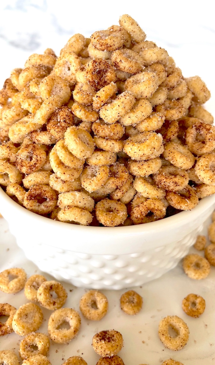 Are you looking for easy homemade snack ideas? Try these Hot Buttered Mini Donut Cheerios! So quick and simple to make with just a few cheap ingredients: Cheerios cereal, butter, sugar and cinnamon! These little treats are great for on the go, road trips, sports practice, movie night, and school lunch boxes. 