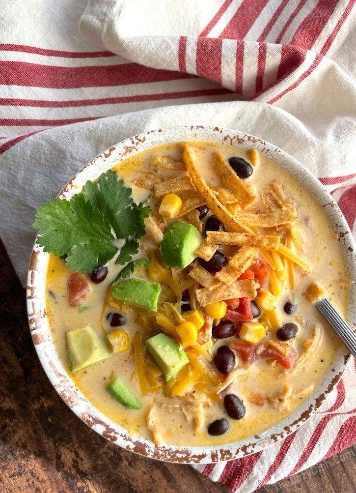 Slow Cooker Creamy Chicken Taco Soup made with chicken breasts, heavy cream, cheddar cheese, beans, corn, tomatoes, chicken broth and taco seasoning. 