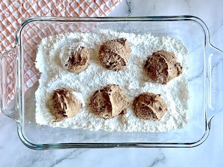 Chocolate Cool Whip Cookies in a bowls of powdered sugar ready for rolling!