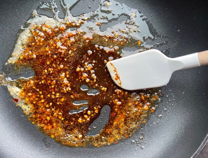 Sweet and spicy sauce in a pan made with soy sauce, brown sugar, minced garlic, and butter ready to be tossed with cooked and drained ramen noodles. 