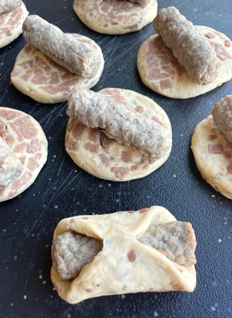 Sausage links wrapped in cinnamon rolls to make breakfast pigs in a blanket, a fun and easy recipe to make at home with just 2 ingredients!