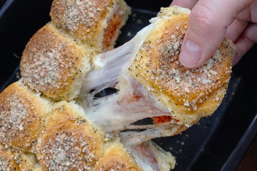 Easy homemade meal made with any brand of frozen chicken nuggets, Hawaiian rolls, marinara or pizza sauce, cheese, and garlic butter.