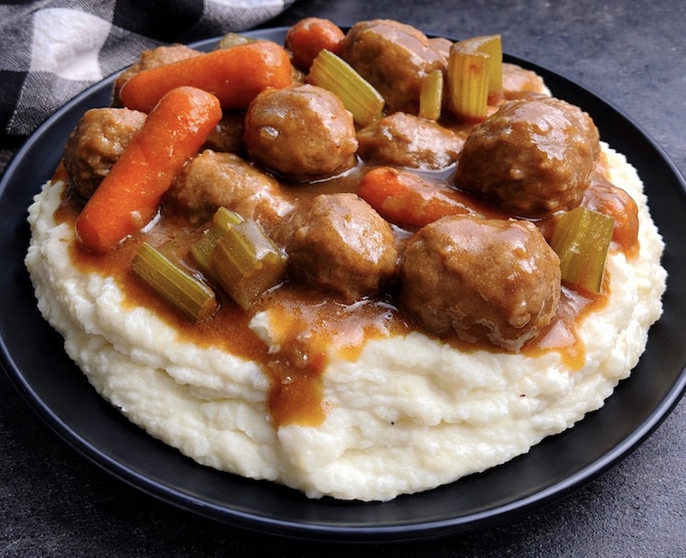 Close up view of a frozen meatball pot roast made in a crockpot over mashed potatoes and gravy. 