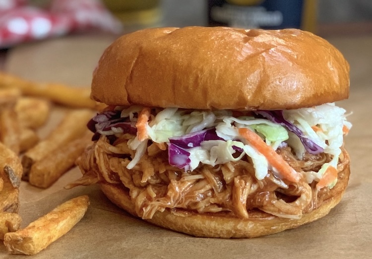 Toasted bun stuffed full of slow cooker shredded bbq chicken and coleslaw with a side of French fries. 
