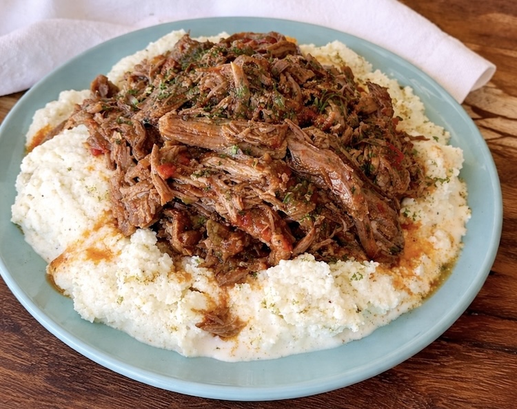 Shredded beef pot roast on a plate with mashed potatoes. 